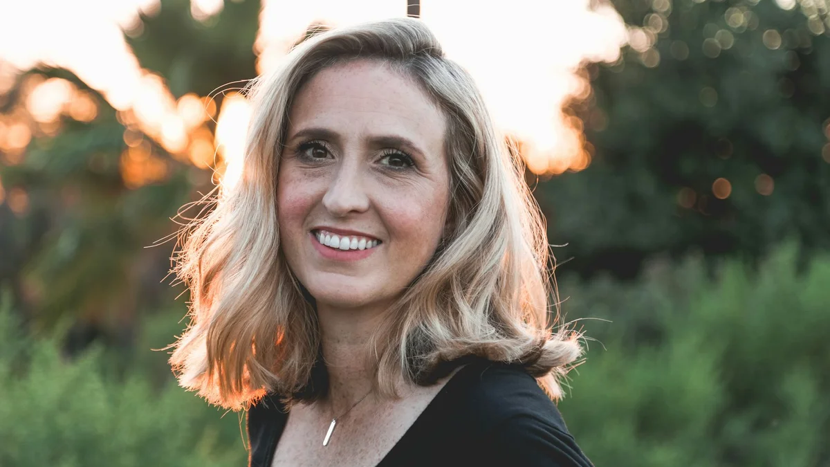 A portrait of a smiling woman with blonde hair at sunset, warm backlight - a Quiet Core Reset guide to When Helping Others Is Actually Hurting You.