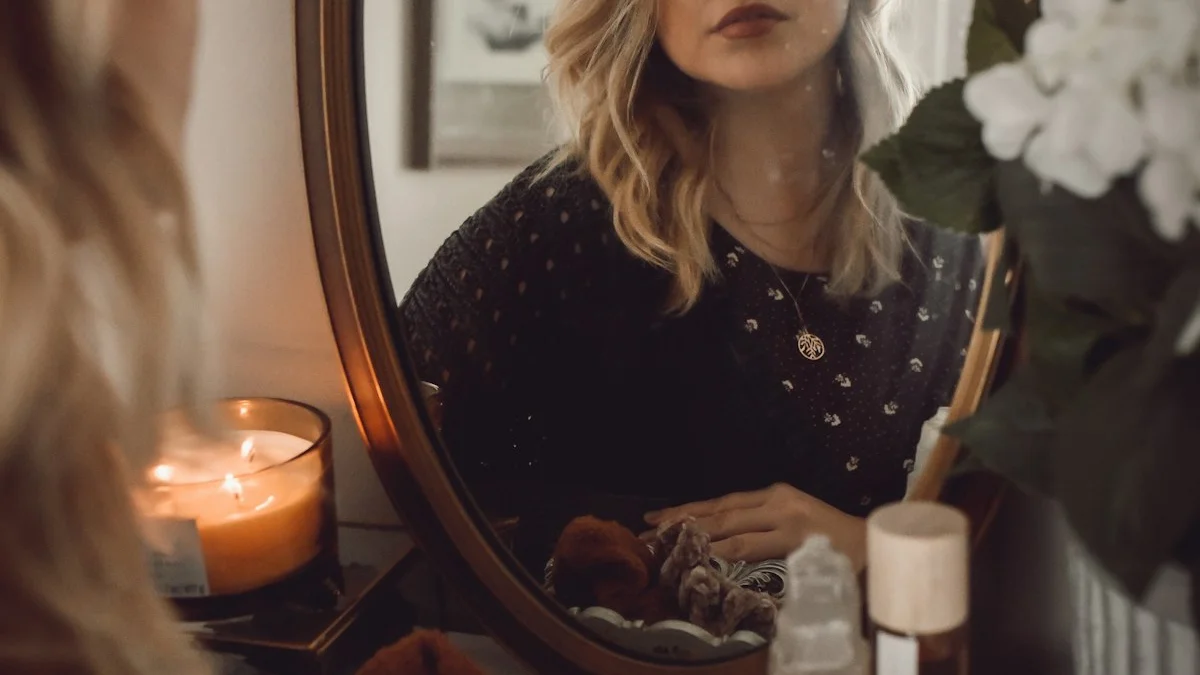 A woman reflected in a round vanity mirror beside a lit candle late at night - a Quiet Core Reset guide to Why You’re Emotionally Exhausted.