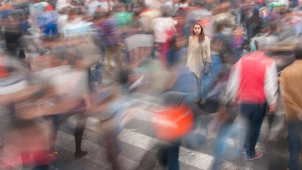 One still figure in a motion-blurred crowd crossing a busy street - a Quiet Core Reset guide to Why Everything Feels Fast.