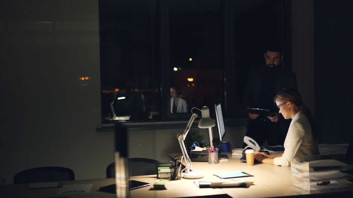 A dim office at night with one worker still at a lamp-lit desk buried in papers and screens - a Quiet Core Reset guide to Why High-Functioning Exhaustion Happens.