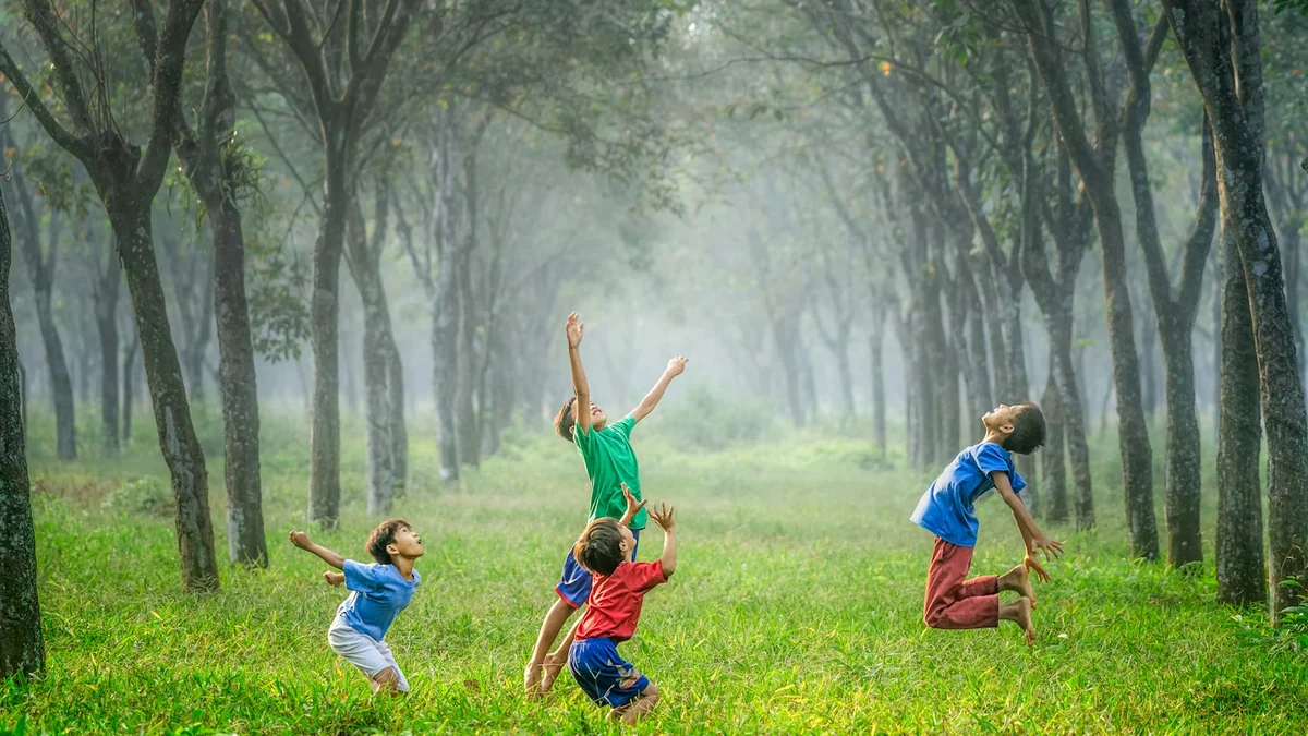 Children playing and jumping joyfully in a misty green forest, full of energy - a Quiet Core Reset guide to Why Most People Are People-Pleasers and How to Stop.