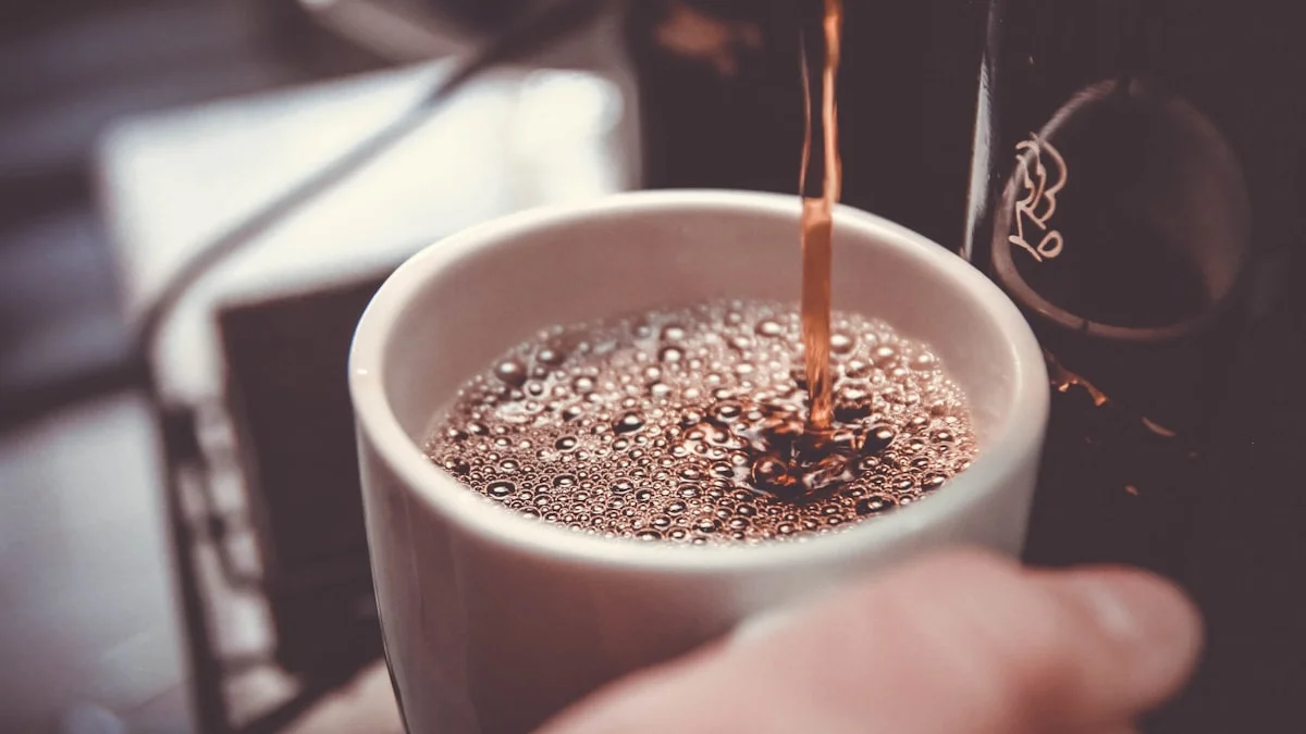 Coffee poured into a white mug held in soft warm light, a quiet pause in an ordinary morning - a Quiet Core Reset guide to Why Self-Care Isn't Working (and What Actually Helps).
