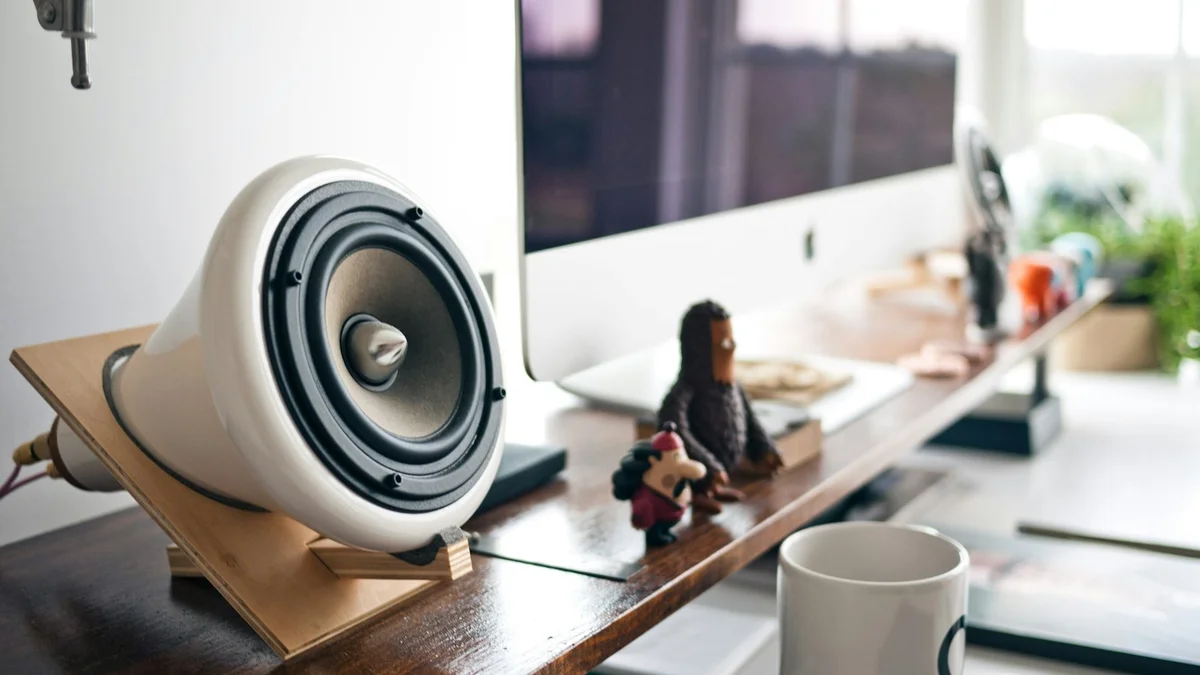 A wooden speaker and a computer on a desk with figurines, a creative workspace - a Quiet Core Reset guide to Why You Can't Stop Saying Yes.
