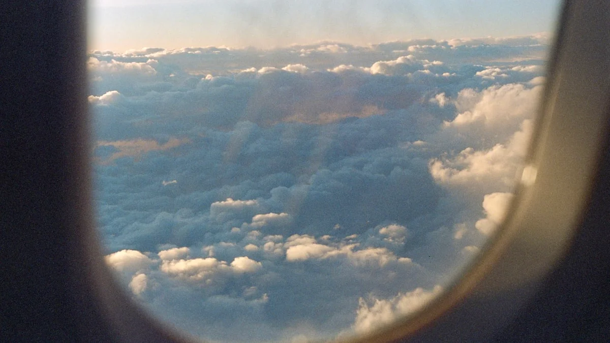 Soft clouds drifting past an airplane window in warm light, weather simply passing through - a Quiet Core Reset guide to Why You Don't Have to 'Fix' Your Emotions.