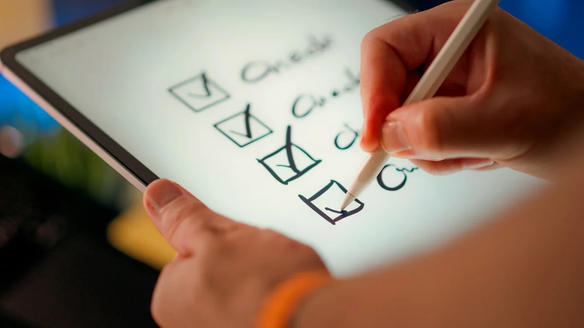 A hand ticking boxes on a checklist with a stylus - a Quiet Core Reset guide to Work Energy Checklist.