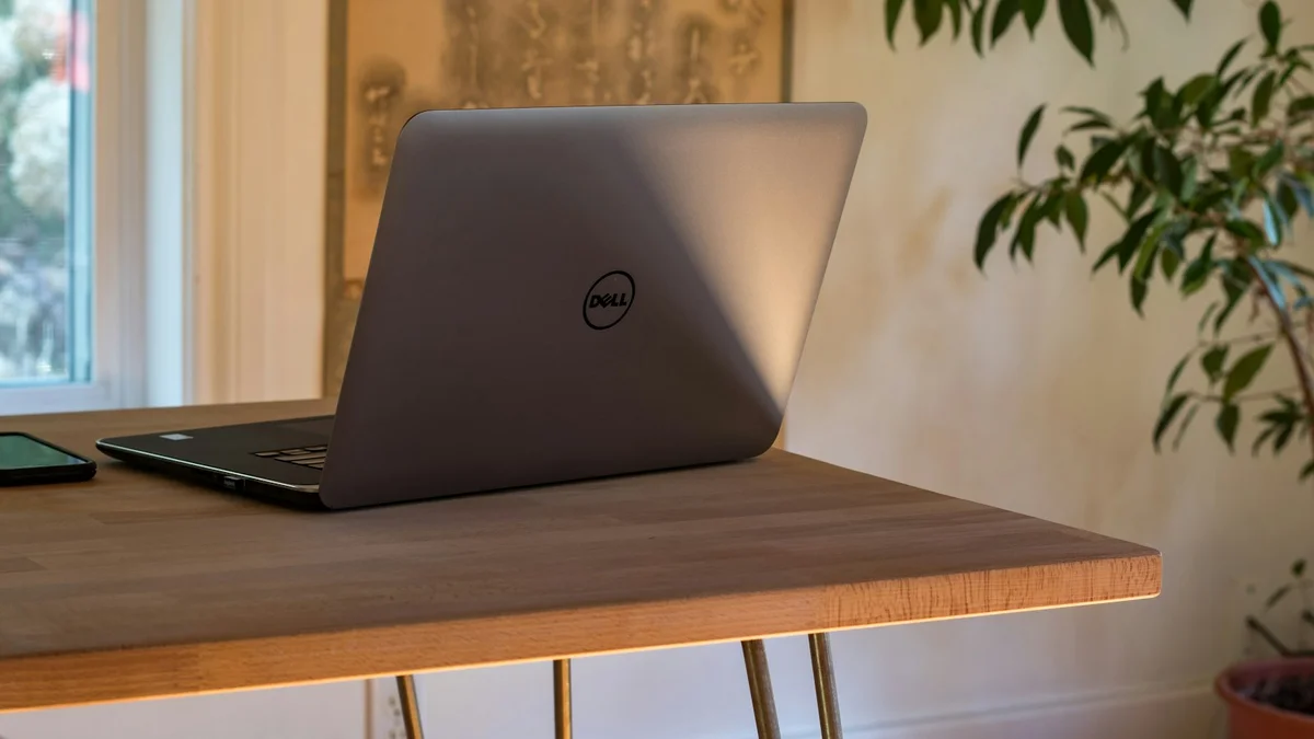 A laptop on a wooden desk beside a bright window and a plant - a Quiet Core Reset guide to Work Energy for Entrepreneurs.